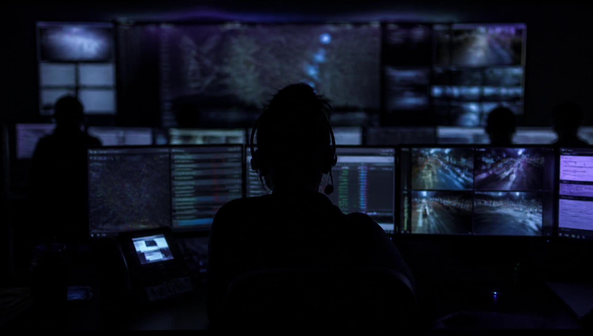 Dispatcher monitoring live feeds in a darkened emergency operations center